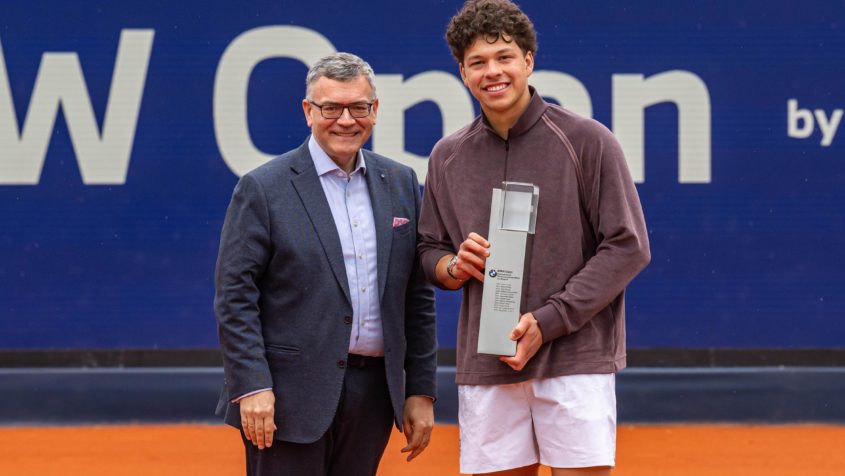 Staatsminister Dr. Florian Herrmann &uuml;berreicht Ben Shelton den Siegerpokal.